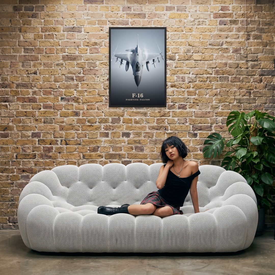 F-16 Fighting Falcon, framed in black, in an industrial loft with tufted sofa