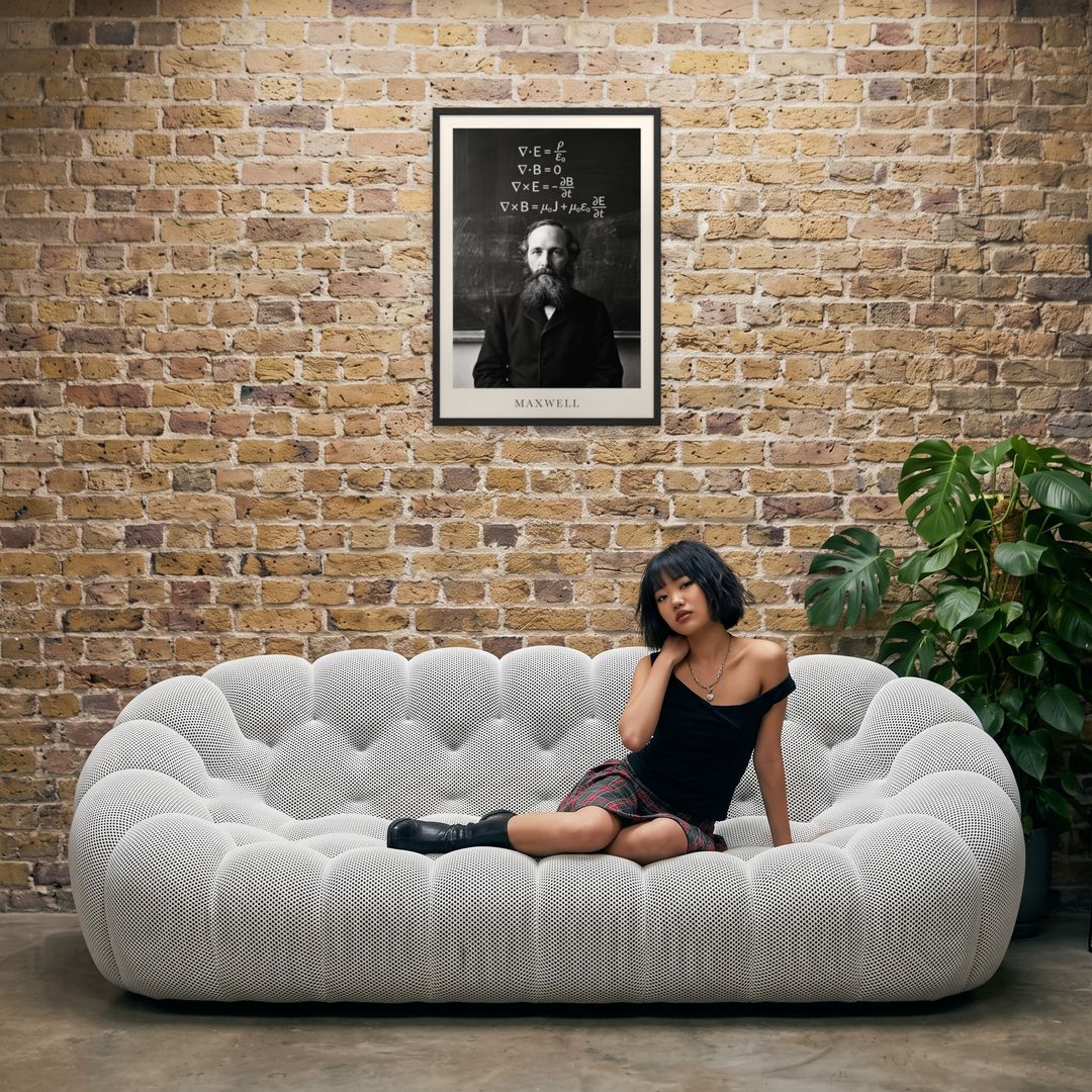 James Clerk Maxwell, framed in black, in an industrial loft with tufted sofa
