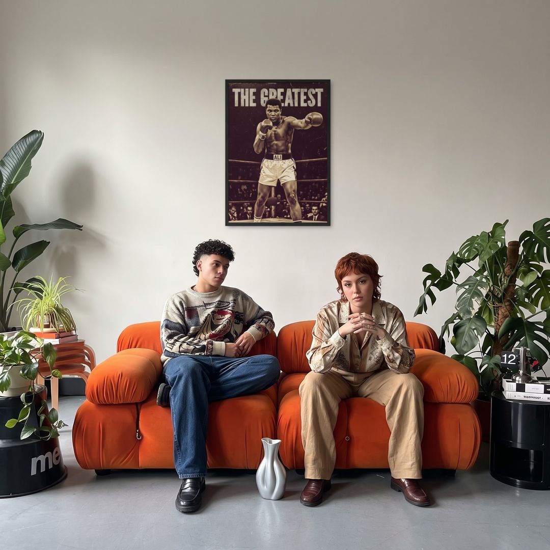 The Greatest, framed in black, in a retro orange sofa lounge