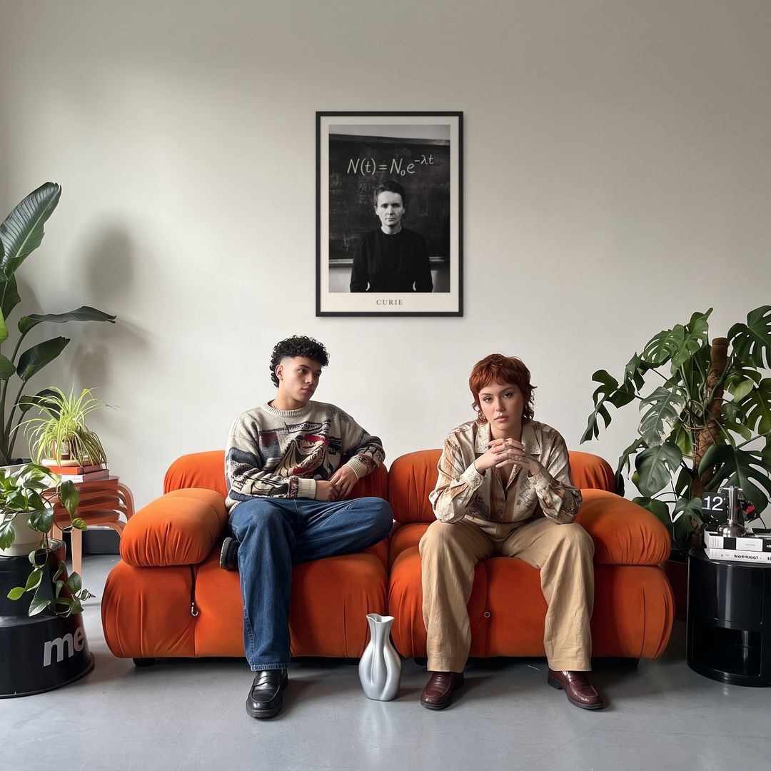 Marie Curie, framed in black, in a retro orange sofa lounge