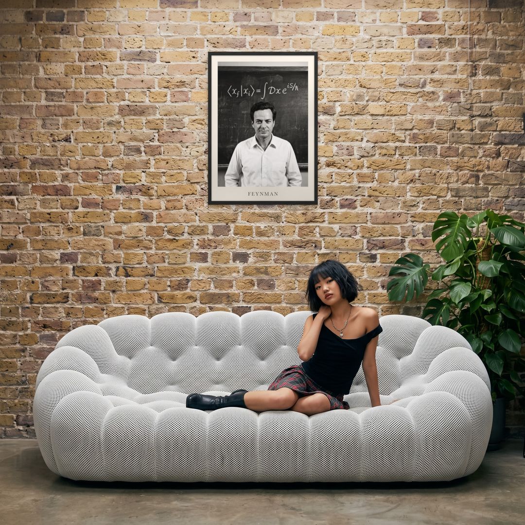 Richard Feynman, framed in black, in an industrial loft with tufted sofa