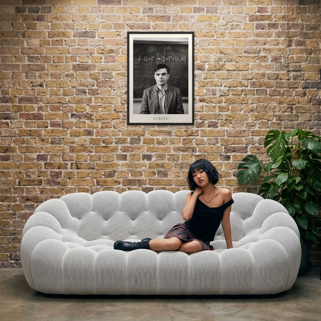Alan Turing, framed in black, in an industrial loft with tufted sofa
